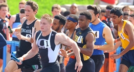 Male runners crowd the turn in a relay race at the 2016 State Championships.