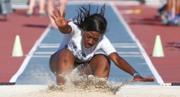 A female triple jumper lands in the sand pit at the end of her jump in the 2018 State Meet.
