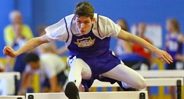 A male hurdler from Crisfield clears a hurdle during a race at the 2017 State Indoor Track & Field Championships.