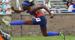 A female hurdler begins to clear a hurdle during a race in the 2017 State Championship meet.