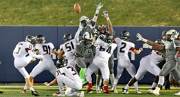 A Linganore kicker attempts to elude the outstretched arms of the Milford Mill defenders in the 2017 State Class 3A Football Final.