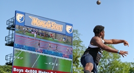 A male shotputter lets it fly with the video scoreboard as a backdrop at the 2018 State Meets.