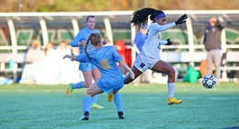A female player avoids the leg tackle of a defender while dribbling the ball during the 2018 State Soccer Finals.