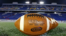 Wilson footballs lined up under the lights on the field at Navy-Marine Corps Memorial Stadium.
