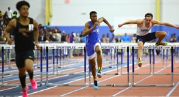 Three hurdlers racing to finish line.