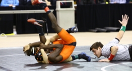 One wrestler prepares to pin another wrestler while the official is flat on the mat counting back points.