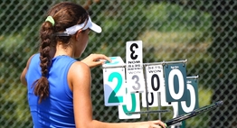 A female tennis player adjusts the flip score at her 2016 State Tournament match.