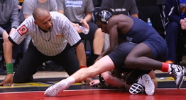 Two wrestlers engage on the mat under an official's watchful eye at the 2019 Dual Meet State Tournament.