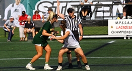 A female lacrosse official oversees a draw about to be taken during the Girls State Lacrosse Finals.