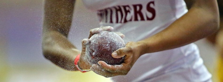 A female shot putter dusts the shot with chalk during the 2019 Class 4A State Indoor Track Meet.