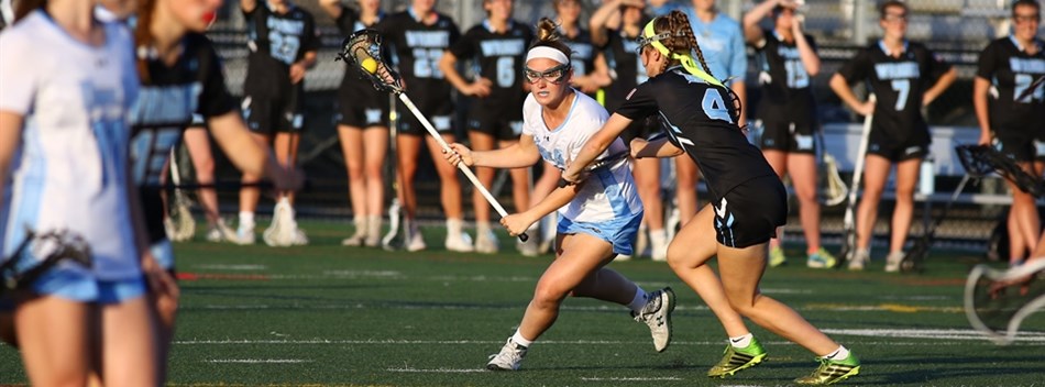 A female player cradles the ball in her stick while closely guarded at the 2019 State 3A Final.