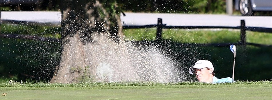 A male golfer blasts a shot out of a bunker during the 2018 State Finals.